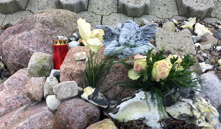 Blumen, eine Kerze und ein Engel am Strand von Bülk