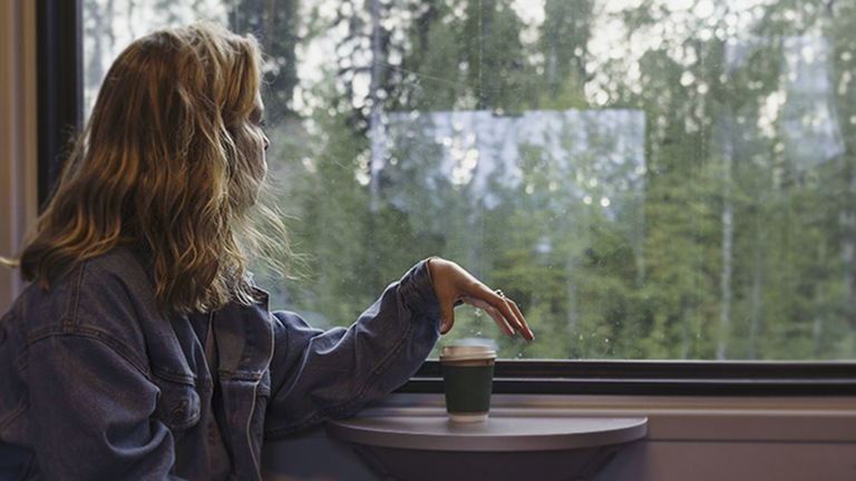 Eine junge Frau schaut aus einem Zugfenster.