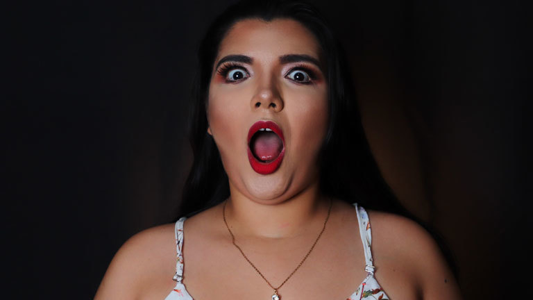 Eine Frau, die überrascht in die Kamera blickt.