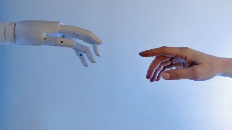 Die Hand eines Roboters und eines Menschen berühren sich fast.