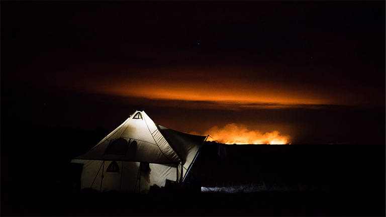Ein Steppenfeuer in der mongolischen Steppe bei Nacht in der Nähe eines Zeltcamps
