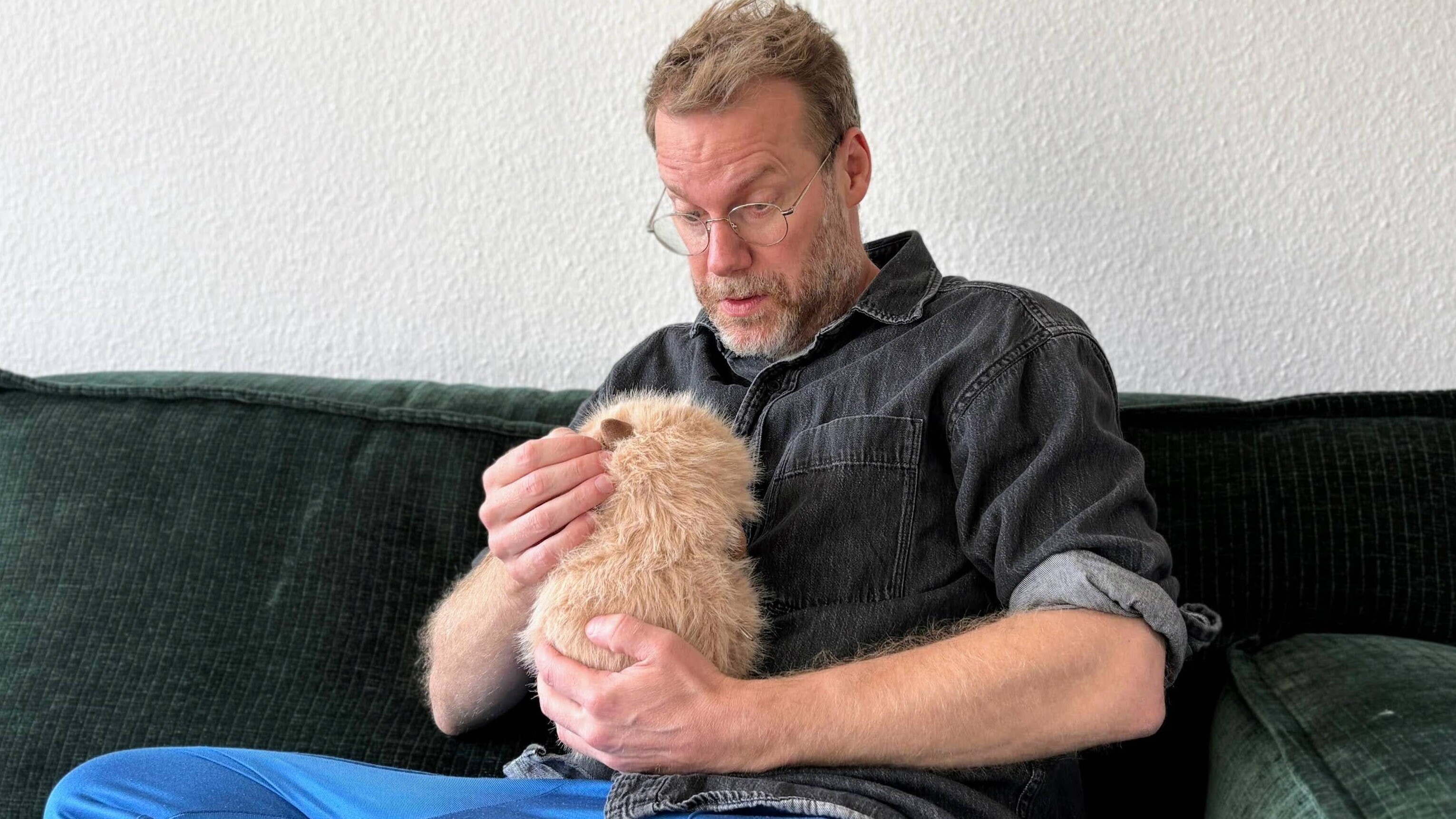 Reporter und Radioautor Christian Schmitt hält ein KI-Kuscheltier auf dem Arm