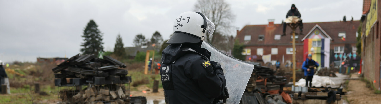 Ein Polizist steht in dem von Klimaaktivisten besetzten Braunkohleort Lützerath. Der Energiekonzern RWE will die unter Lützerath liegende Kohle abbaggern - dafür soll der Weiler auf dem Gebiet der Stadt Erkelenz am Braunkohletagebau Garzweiler II abgerissen werden. Die Polizei hat mit der Räumung des Ortes begonnen.