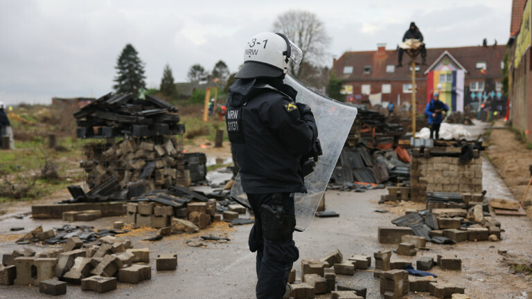 Ein Polizist steht in dem von Klimaaktivisten besetzten Braunkohleort Lützerath. Der Energiekonzern RWE will die unter Lützerath liegende Kohle abbaggern - dafür soll der Weiler auf dem Gebiet der Stadt Erkelenz am Braunkohletagebau Garzweiler II abgerissen werden. Die Polizei hat mit der Räumung des Ortes begonnen.