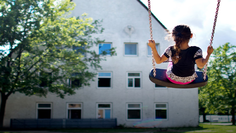Ein Flüchtlingskind auf einer Schaukel