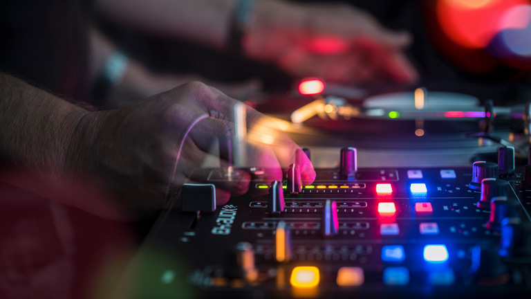 Hand schiebt Regler an einem Mischpult