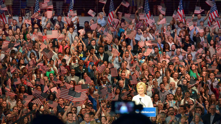 Hillary Clinton vor Flaggen schwenkenden Fans