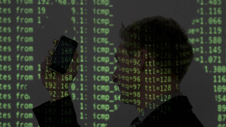 Silhouette eines Mannes mit Handy, beleuchtet mit Ausgaben eines Terminalprogramms