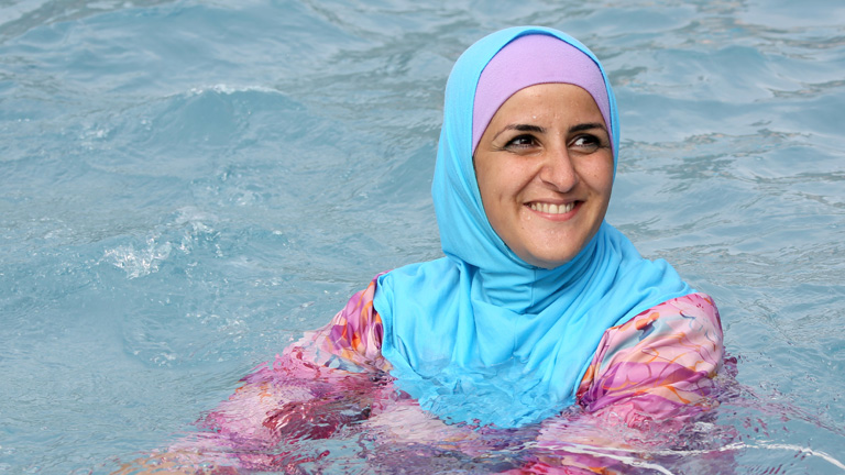 Eine Frau kühlt sich im Burkini im Wasser ab.