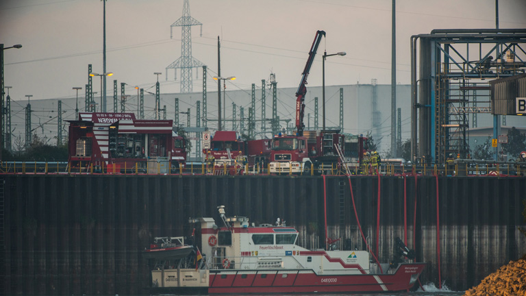 Einsatzkräfte und ein Schiff der Feuerwehr arbeiten an der Unglücksstelle auf dem Werksgelände der BASF in Ludwigshafen
