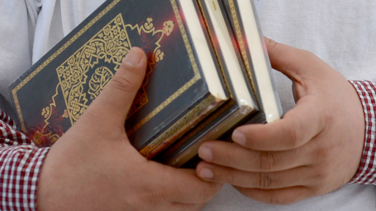 Mann mit Koran-Büchern in der Hand