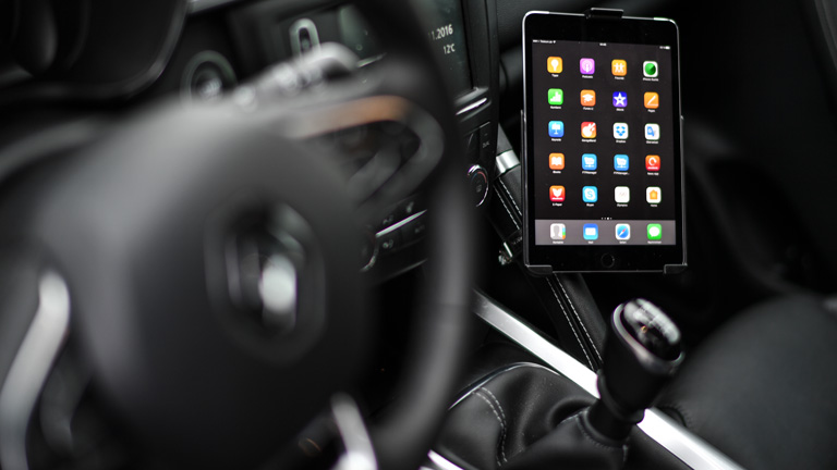 Ein Tablet hängt in einer Halterung neben dem Steuer im Auto.