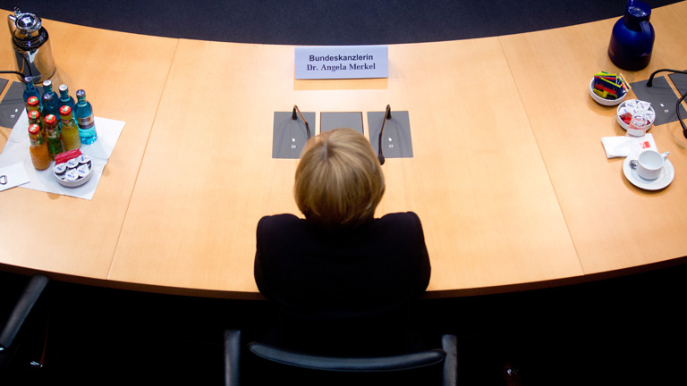 Bundeskanzlerin Angela Merkel sitzt an einem Konferenztisch.