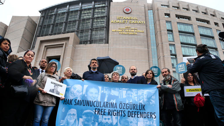 Menschenrechts-Aktivisten demonstrieren am 25.10.2017 vor einem Gericht in Istanbul (Türkei) mit einem Transparent mit Bildern der Angeklagten gegen den Prozess gegen elf Menschenrechtler, darunter auch der Deutsche Peter Steudtner (auf dem Banner der 2.v.r. unten). Die Staatsanwaltschaft wirft den Angeklagten «Mitgliedschaft in einer bewaffneten Terrororganisation» beziehungsweise «Unterstützung von bewaffneten Terrororganisationen» vor.