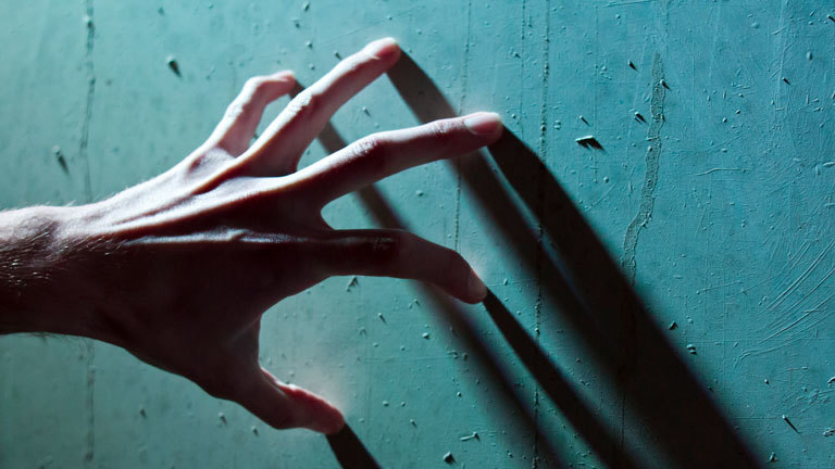 Hand steift mit Fingern über eine Wand