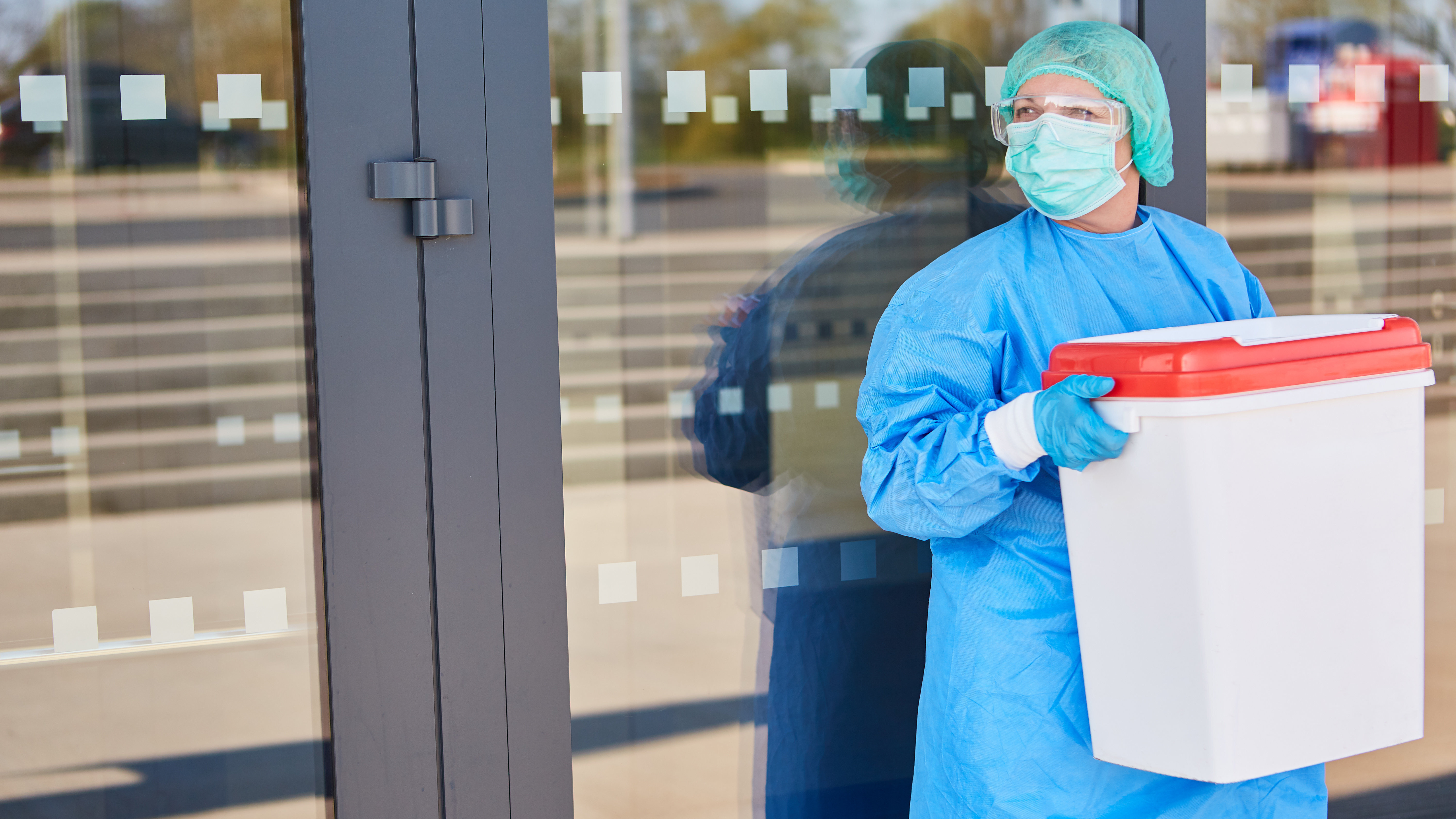 Eine Ärztin in Schutzanzug mit Organspende-Container