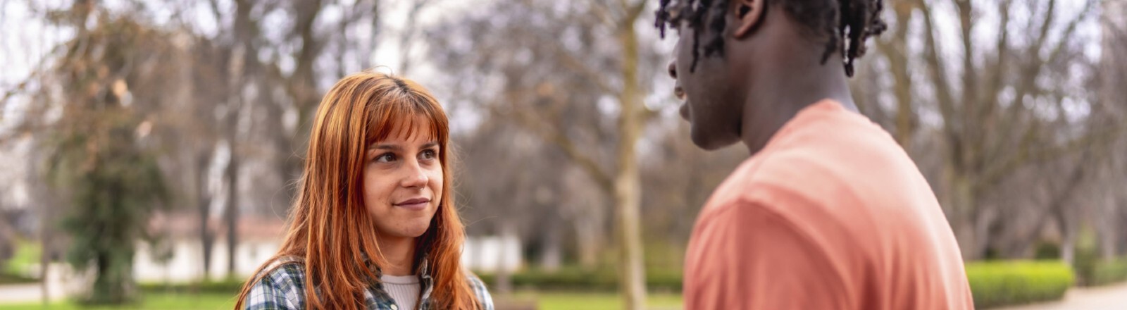 Eine junge Frau und ein junger Mann stehen sich gegenüber. Sie halten Händchen.