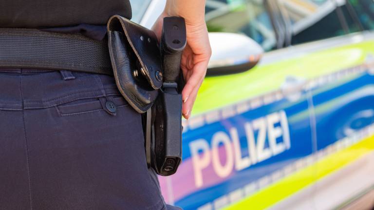 Polizistin mit Waffe und Dienstwagen
