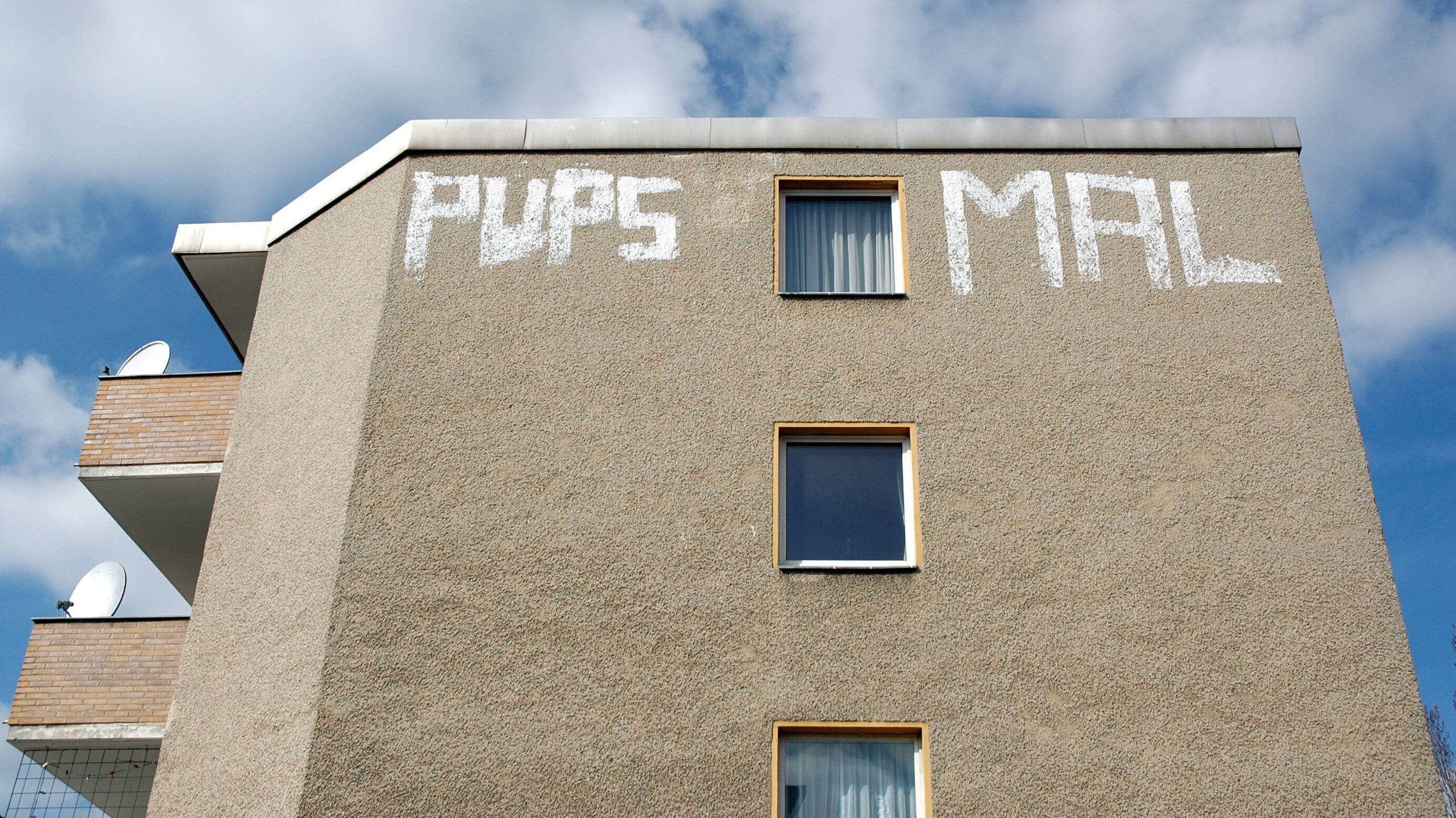 "Pups mal" steht als Graffiti an einer Häuserwand in Berlin