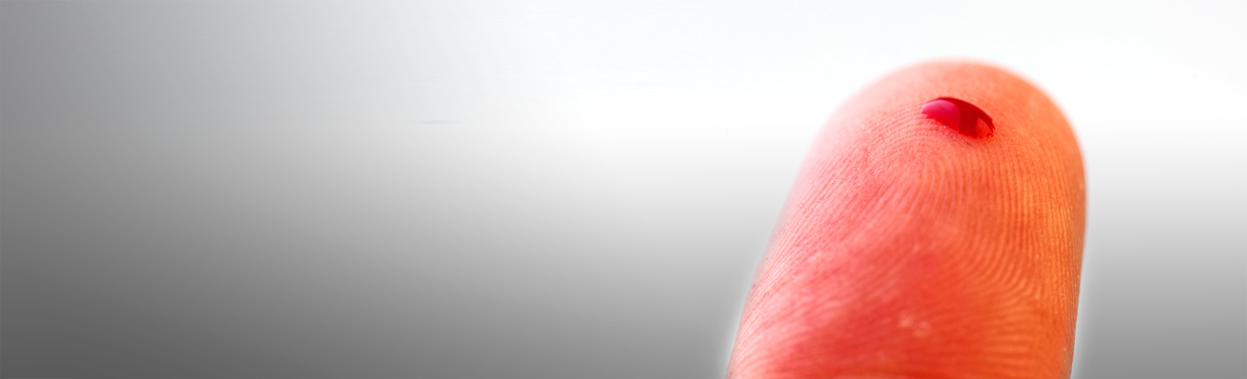 Ein Tropfen Blut auf einem Finger.