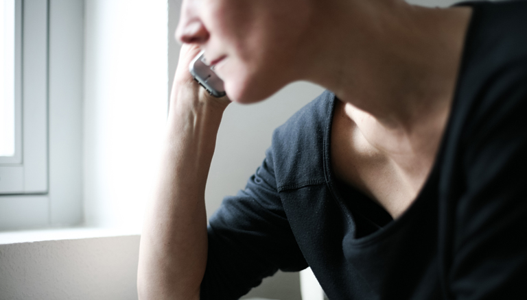 Ein telefonierender Mensch am Fenster.