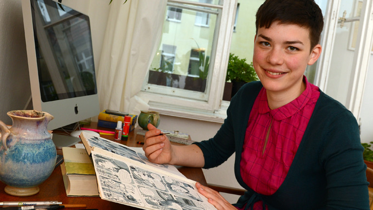 Paula Bulling an ihrem Schreibtisch mit einem Pinsel in der Hand.