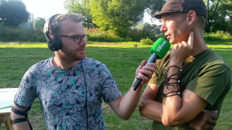 Christian Schmitt mit Mikrofon. Neben ihm steht Lars Christensen, er trägt grünes T-Shirt und eine braune Schirmmütze.