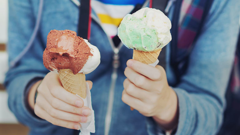 Eine Person hält zwei Tüten mit Eis.