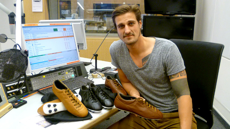 Markus Stolla, Entwickler eines Retro-Fußballschuhs, mit ein paar Schuhen im DRadio-Wissen-Studio