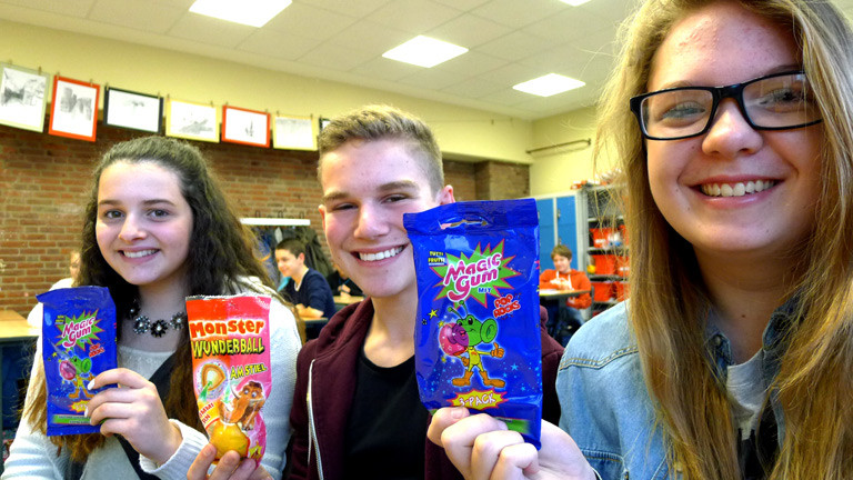 Drei Schüler einer neunten Klasse mit Süßigkeiten der 90er-Jahre.