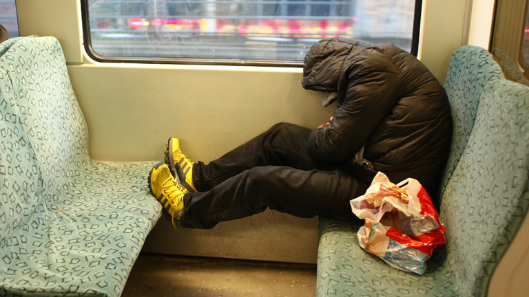 Ein Mann sitzt in einer S-Bahn und schläft.