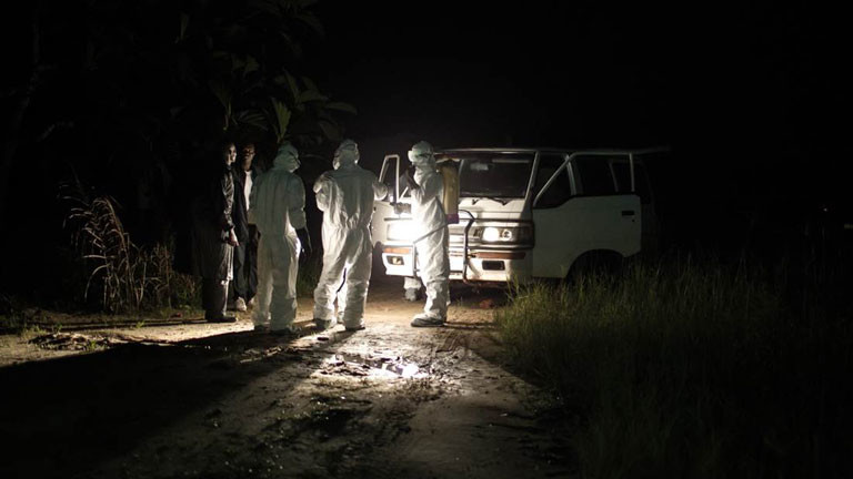 Ein Bestattungsteam in Liberia bereitet sich nachts darauf vor einen Ebolatoten aus einer Baracke zu holen.