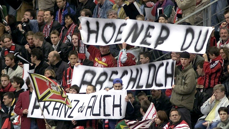 Fans von Bayer 04 Leverkusen halten ein Transparent mit der Aufschrift "Hoeneß Du Arschloch - FRanz auch" in die Höhe.