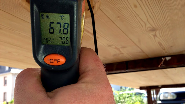 Unterhalb des Solarluftkollektors misst Holger Beetz mit einem elektronischen Thermostat die Temperatur im Kollektor.