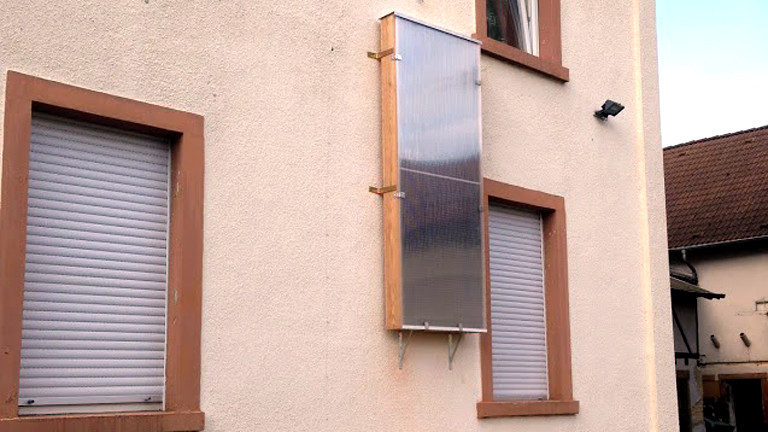 An der Hauswand hängt der fertige Solarluftkollektor