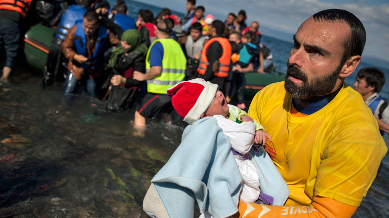 Am 29.10.2015 kommen Flüchtlinge auf Lesbos an, ein frewilliger Helfer hält ein Baby in den Armen.