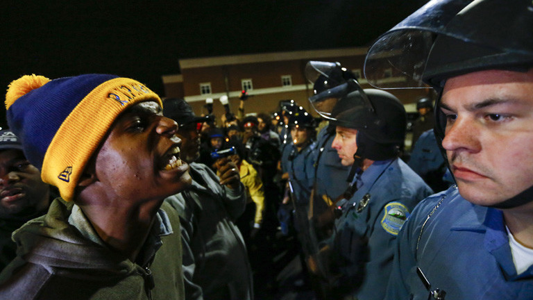 Bei einem Protest in der US-Stadt Ferguson (10.10.2014) stehen sich Demonstranten und Polizisten gegenüber. Einer der Demonstranten spricht auf einen der Polizisten ein; Foto: dpa