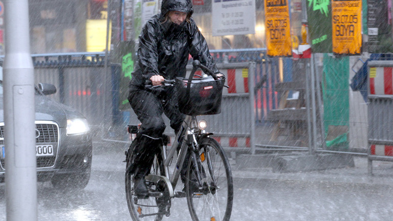 Frau fährt bei Regen in Berlin Fahrrad.