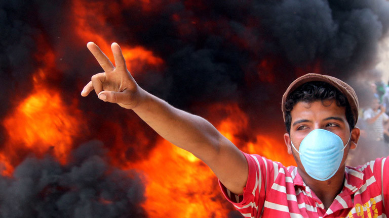 Ein junger Mann vor Flammen auf dem Tahrir-Platz in Ägypten