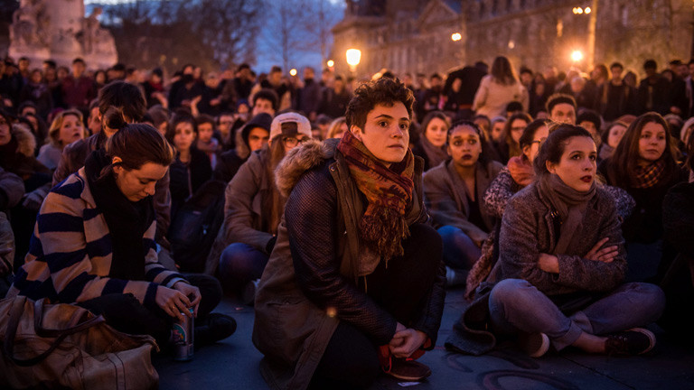 Junge Leute sitzen während einer Demo in der Nacht am Platz der Republik in Paris.