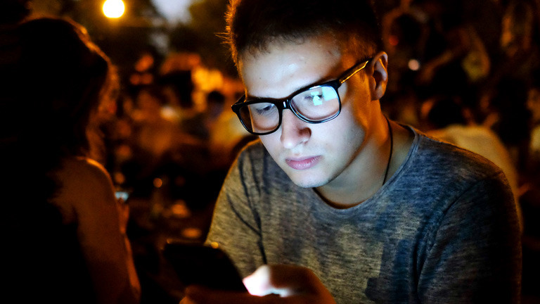 Ein junger Mann schaut auf sein Handy