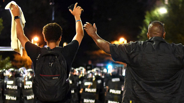 Protestler heben vor der Polizei in Charlotte, North Carolina die Hände