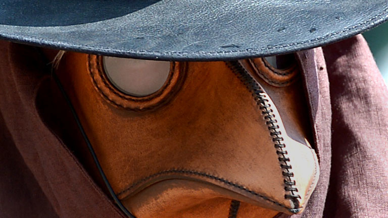 Ein Mann trägt ein Pestmaske. Mit solchen Masken wurden früher Menschen behandelt, die an der Pest erkrankt sind.