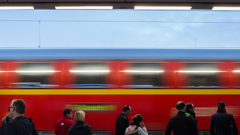 Menschen im Bahnhof, Zug fährt vorbei