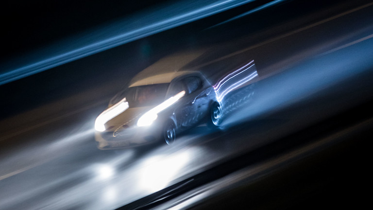 Ein Auto bei Nacht mit Schweinwerferlicht, verschwommen