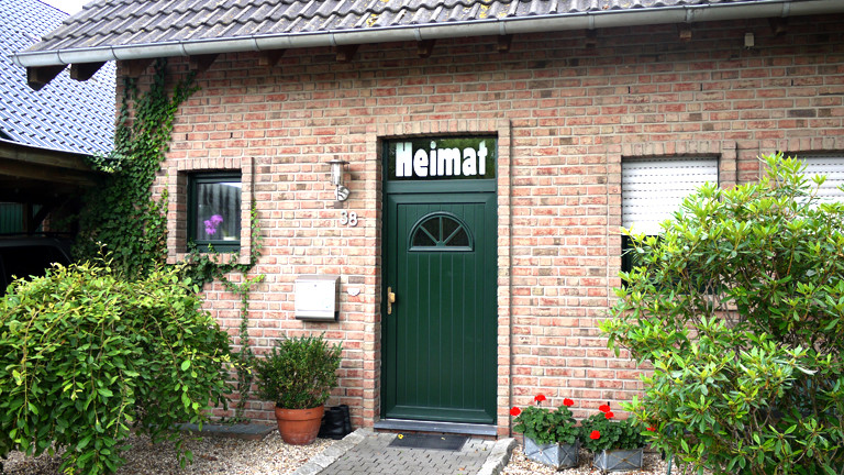 Im Fenster einer Haustür steht Heimat