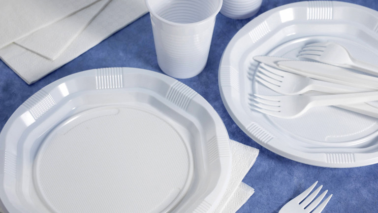Weißes Plastikgeschirr und -besteck auf blauer Tischdecke