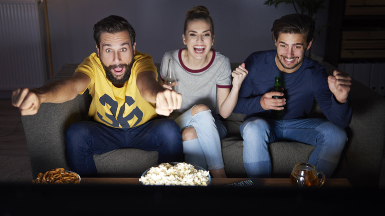 drei Menschen schauen Fußball auf einer Couch