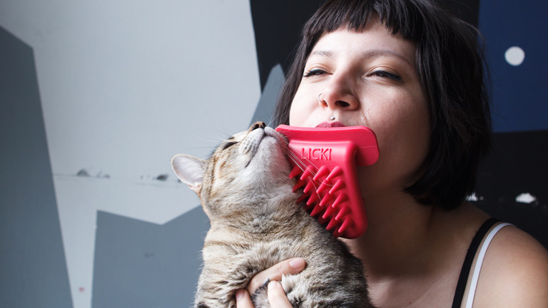 Eine Frau schleckt eine Katze mit einer Plastikzunge