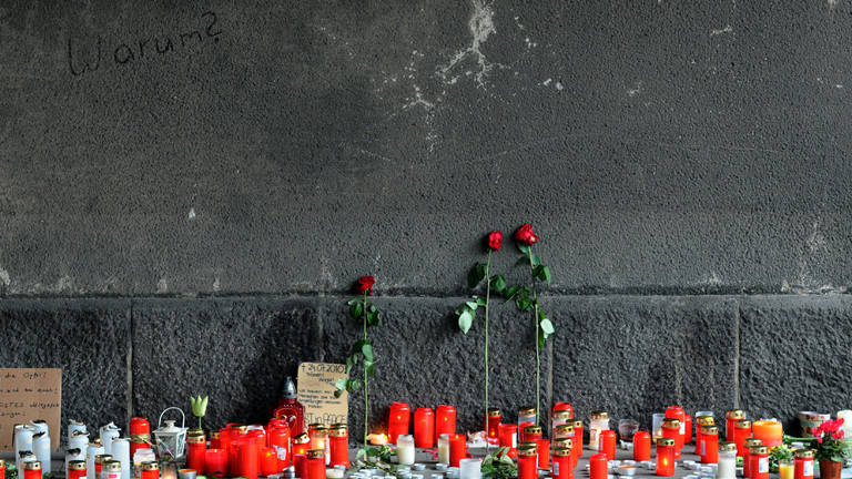 Blumen und Kerzen für die Opfer stehen an der Wand des Tunnels, in dem bei der Loveparade mehrere Menschen getötet wurde.